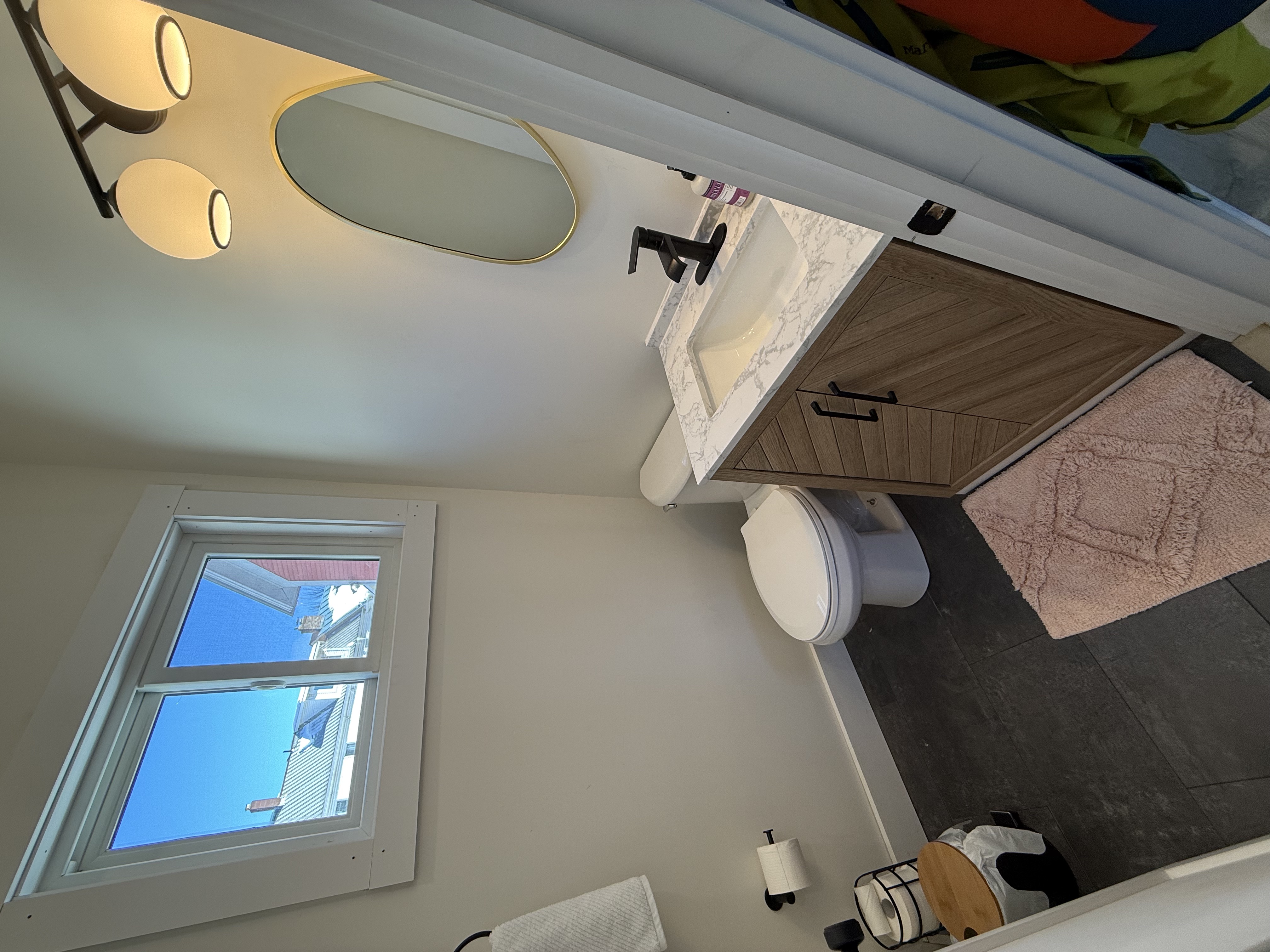 Half bathroom with oval mirror and marble-top vanity