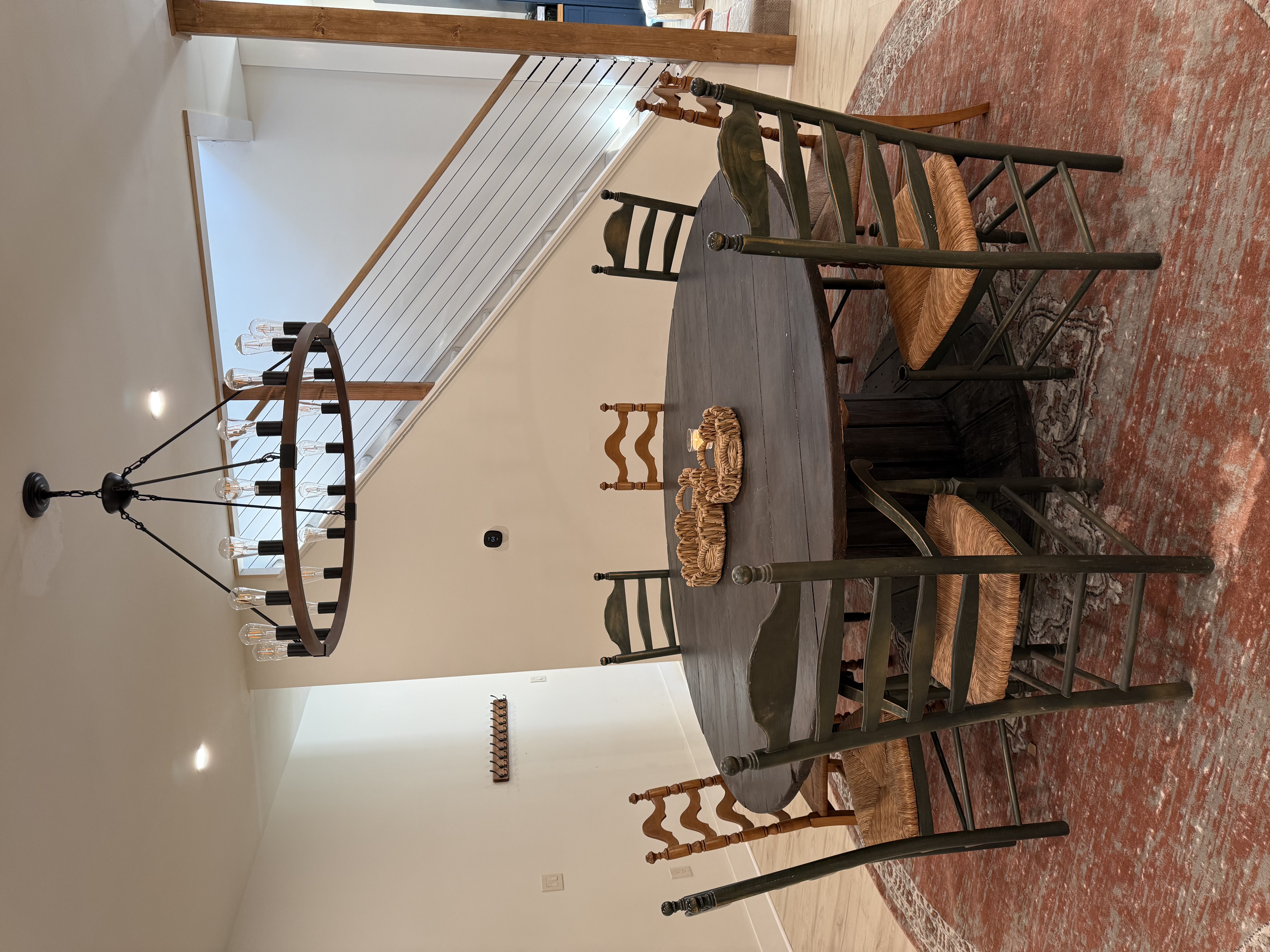 Round dining table seating eight under a wagon-wheel chandelier