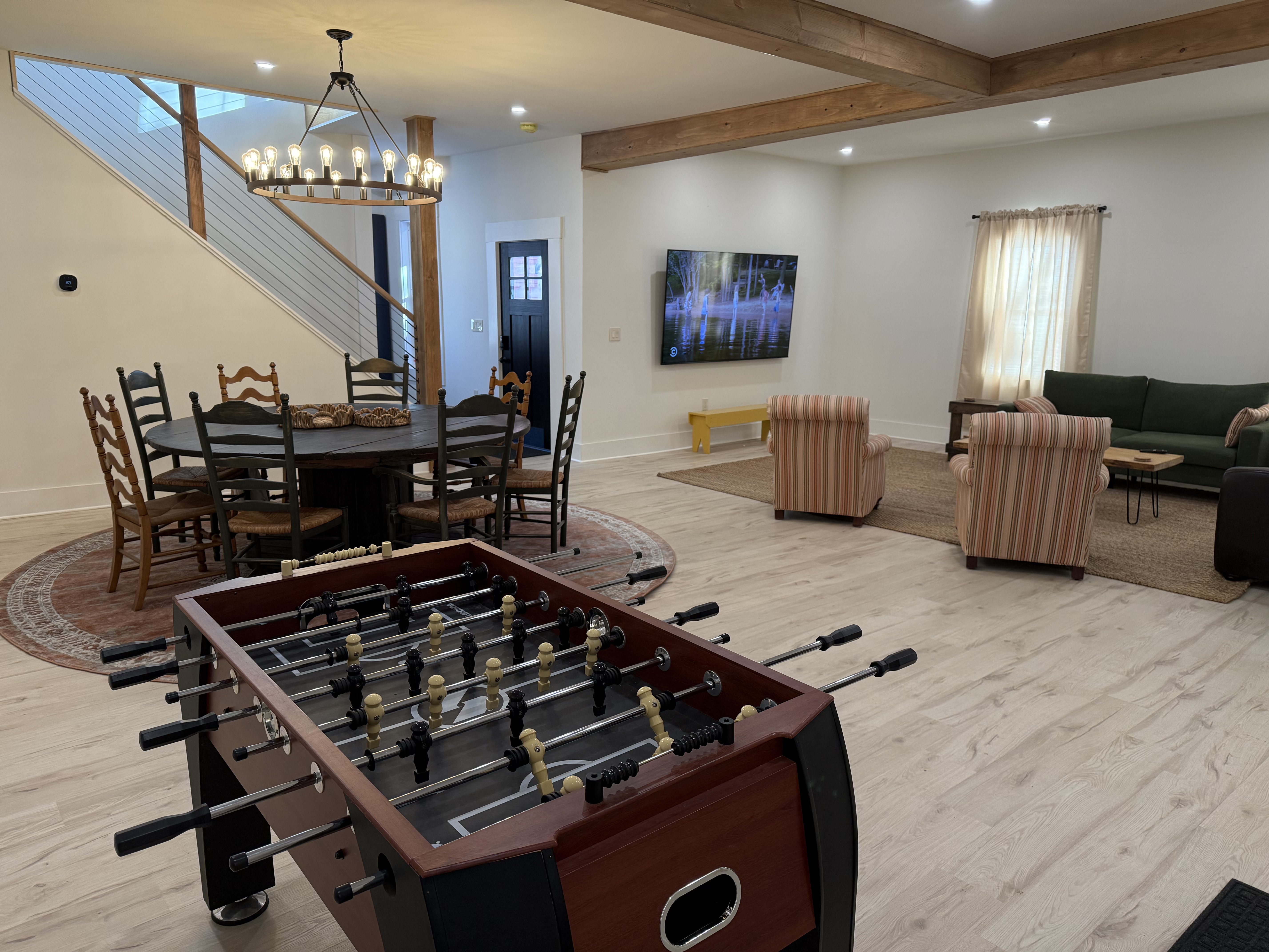 Game room with foosball table, TV, and dining area beyond