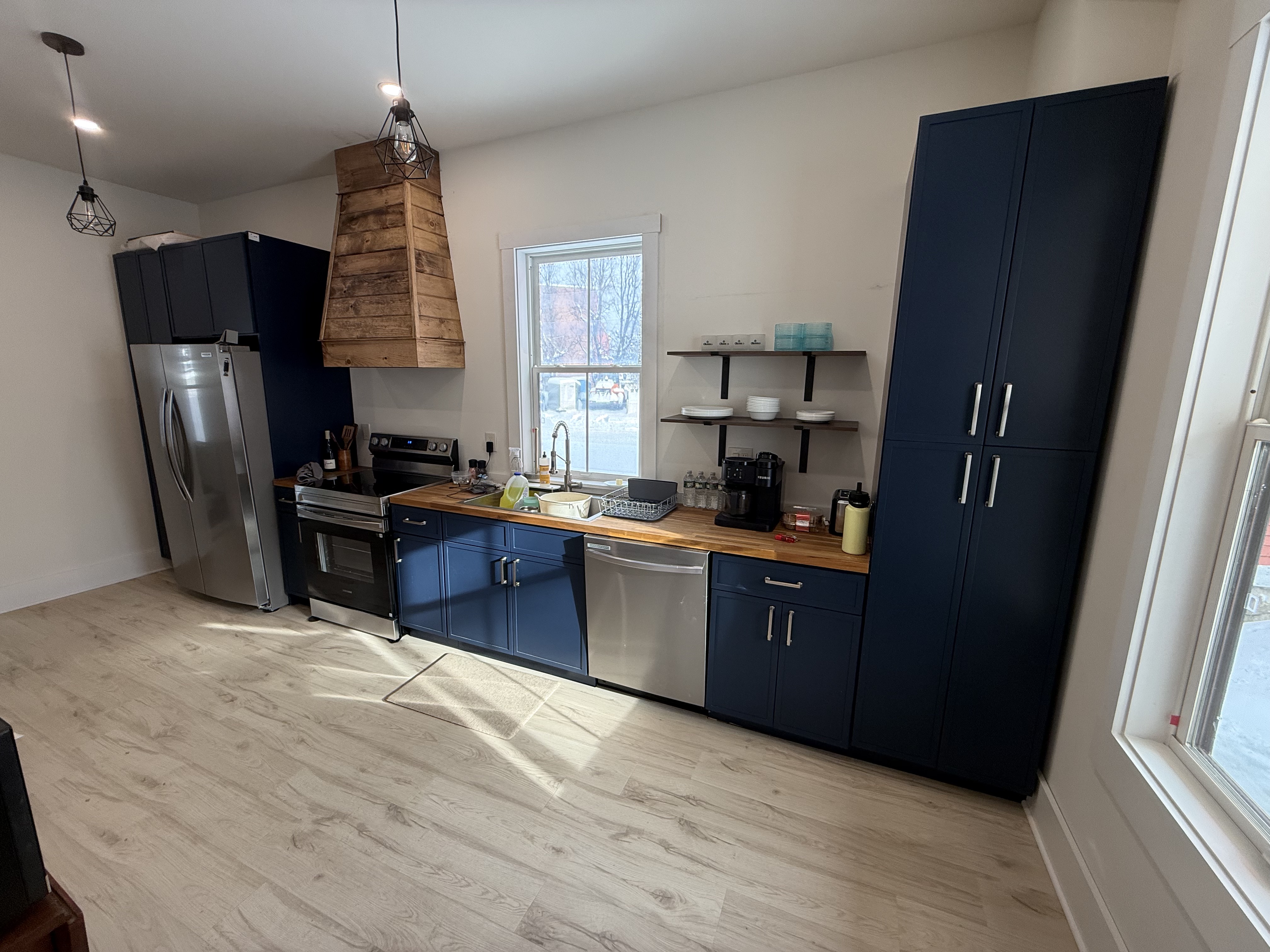 Kitchen with navy cabinets and butcher block counters, daytime