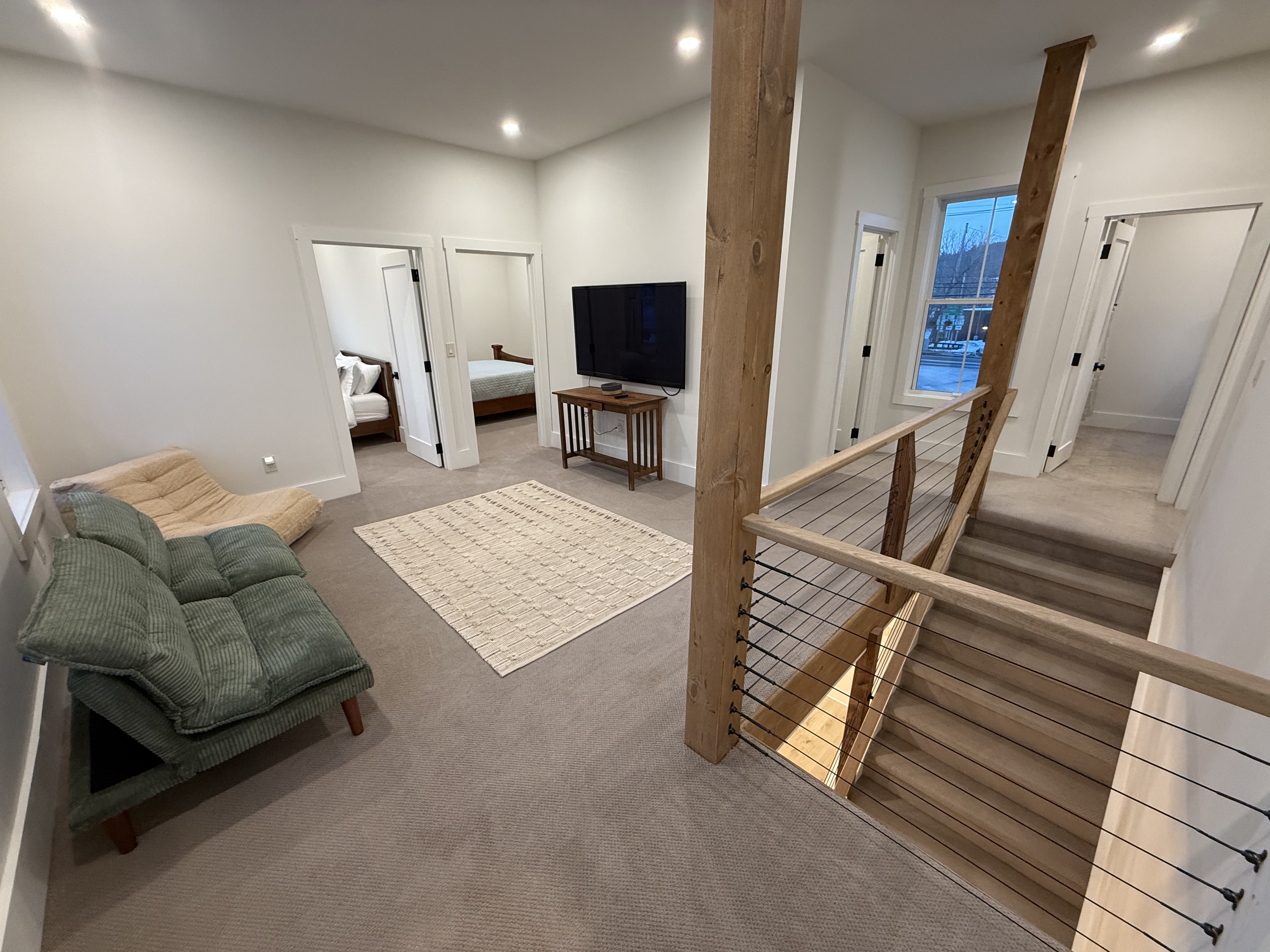 Upstairs lounge with sofa, chaise, and TV outside two bedroom doors